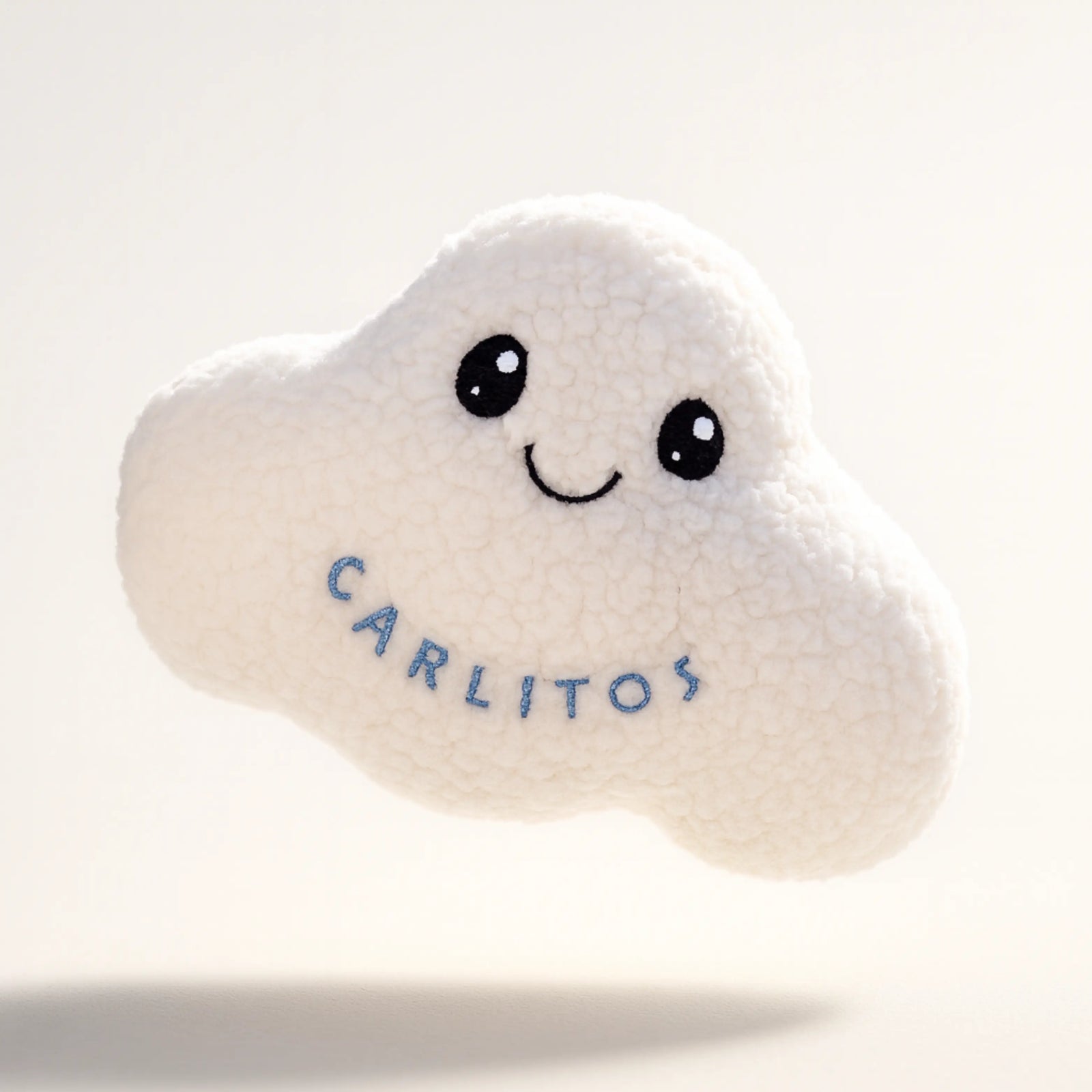 White cloud-shaped plush toy with 'Carlitos' embroidery on a light gray background