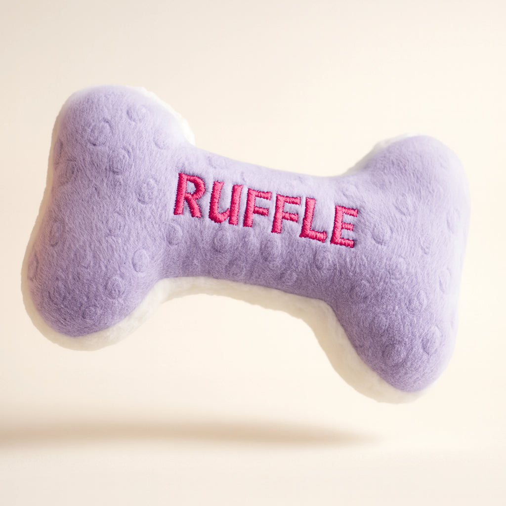 Purple bone-shaped dog toy with 'RUFFLE' embroidered on it against a light background