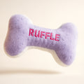 Purple bone-shaped dog toy with 'RUFFLE' embroidered on it against a light background