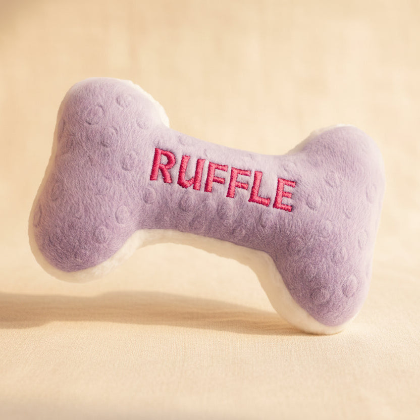 Purple bone-shaped dog toy with 'RUFFLE' embroidered on it against a light background