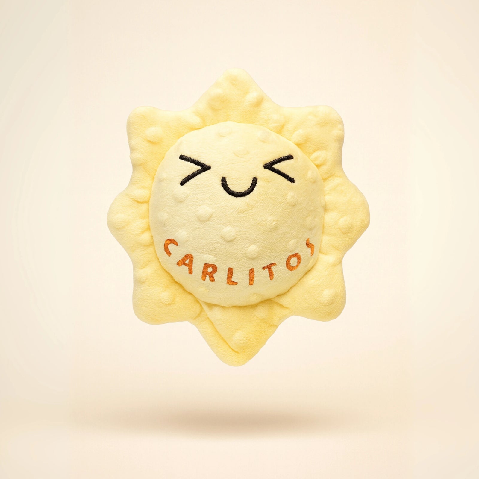 Sun-shaped plush toy with 'Carlitos' branding on a beige background