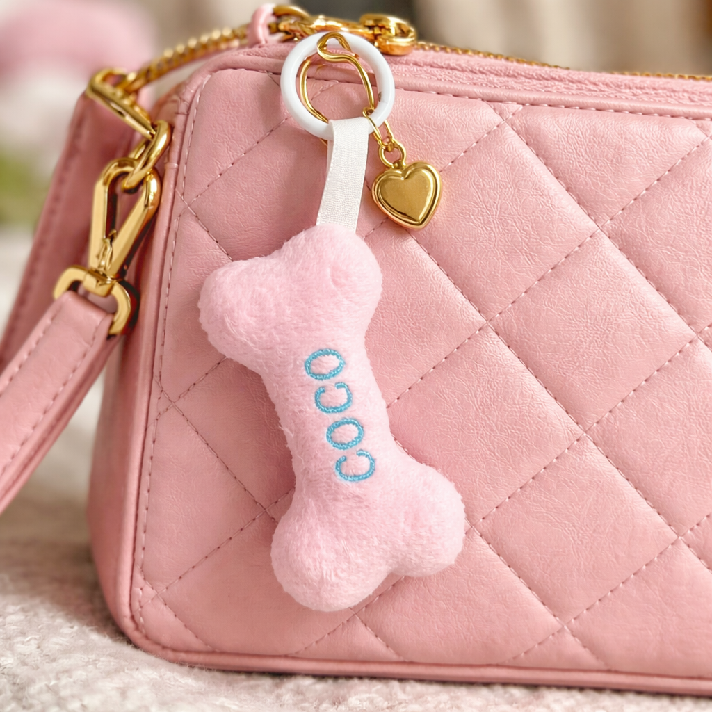Pink quilted handbag with a bone-shaped keychain featuring the word 'COCO'.