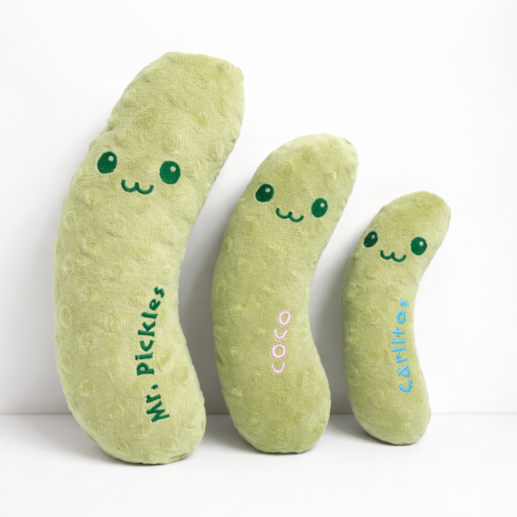 Three plush pickle toys with faces on a white background